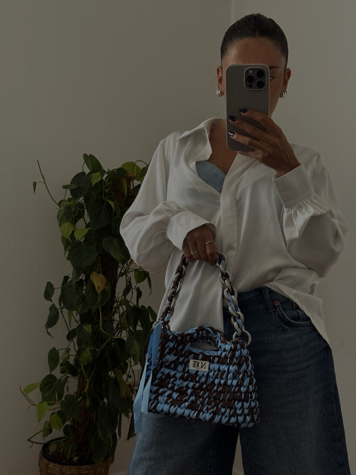 Stefania con camicia bianca, jeans e borsa crochet azzurra e marrone
